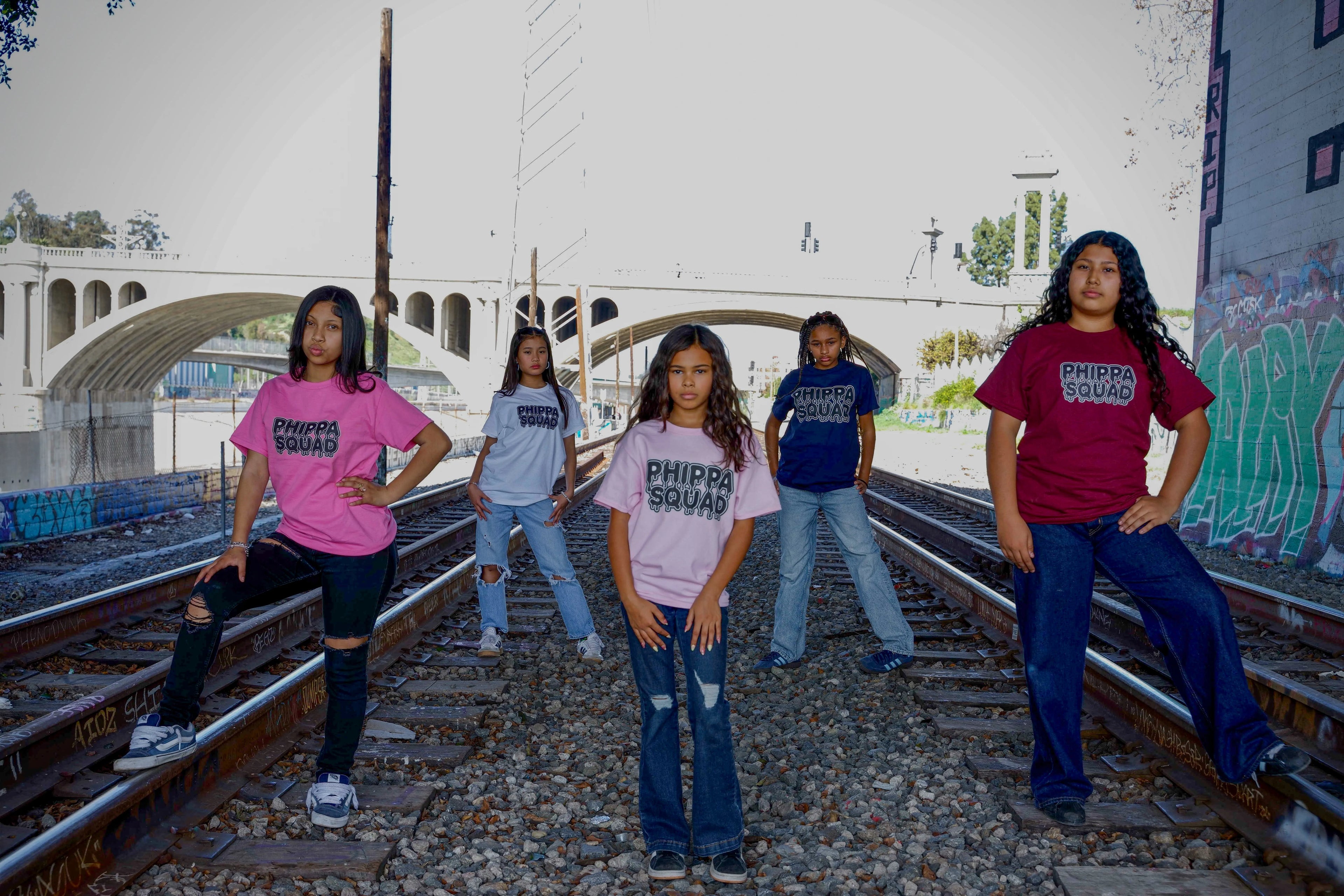 Five girls wearing Phippa Squad tees on train tracks with LA bridge and graffiti in background - streetwear crew